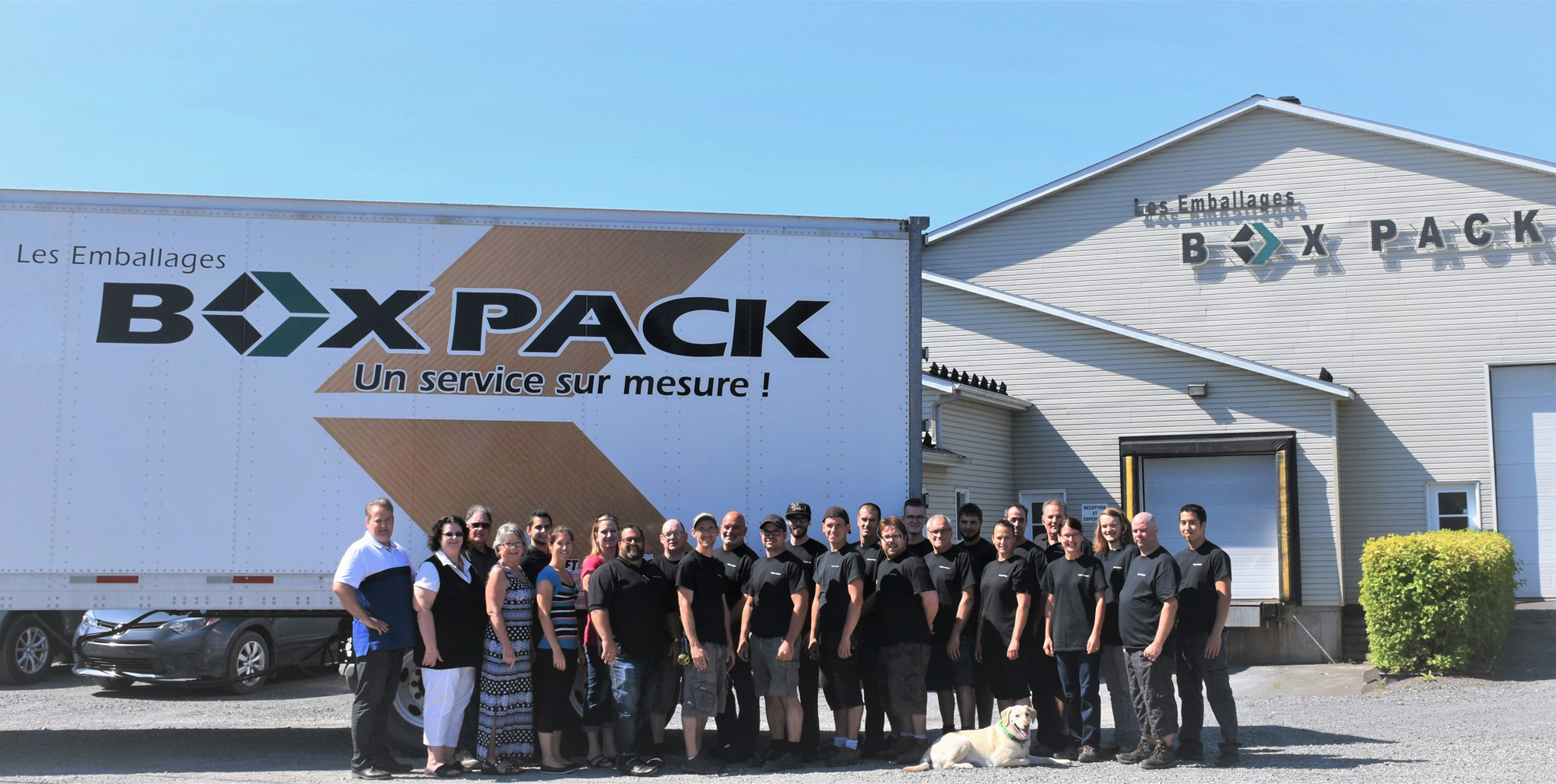 Photo de l'équipe Box Pack devant l'une des usines et un camion de livraison avec leur logo. 